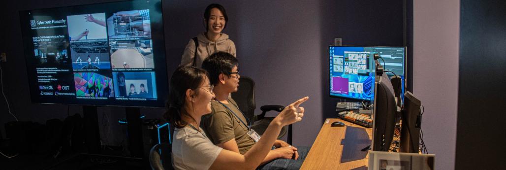 3 researchers are looking at the computer screen and smiling